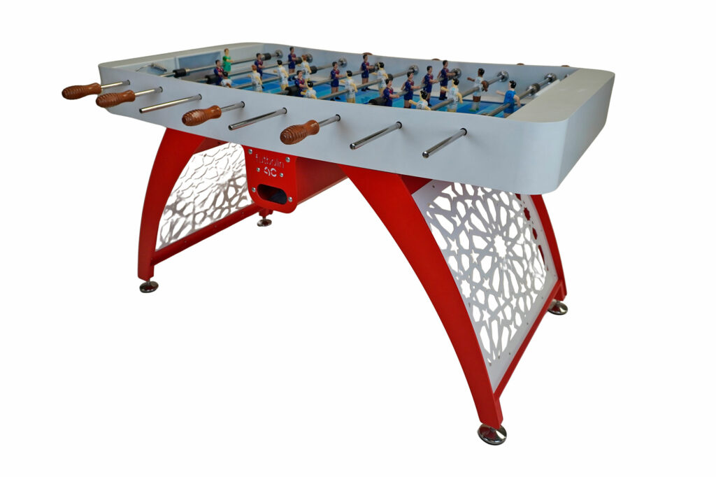 Modelo lacado en blanco y rojo con patas diseño árabe, pista en tonos azules y jugadores con equipaciones clásicas del Real Madrid y F. C. Barcelona. Incluye mangos de iroko natural. Disponible con o sin monedero.